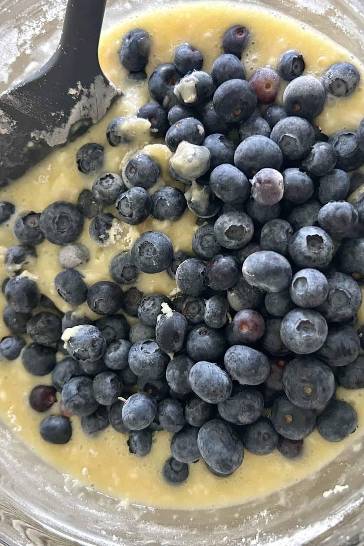 Add fresh blueberries to the batter in the glass bowl