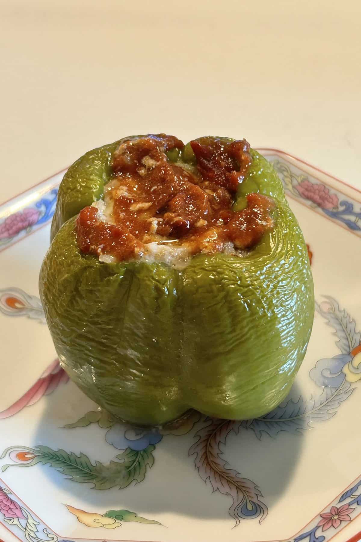 Baked stuffed peppers with tomato paste on top in a beautiful Chinese dish