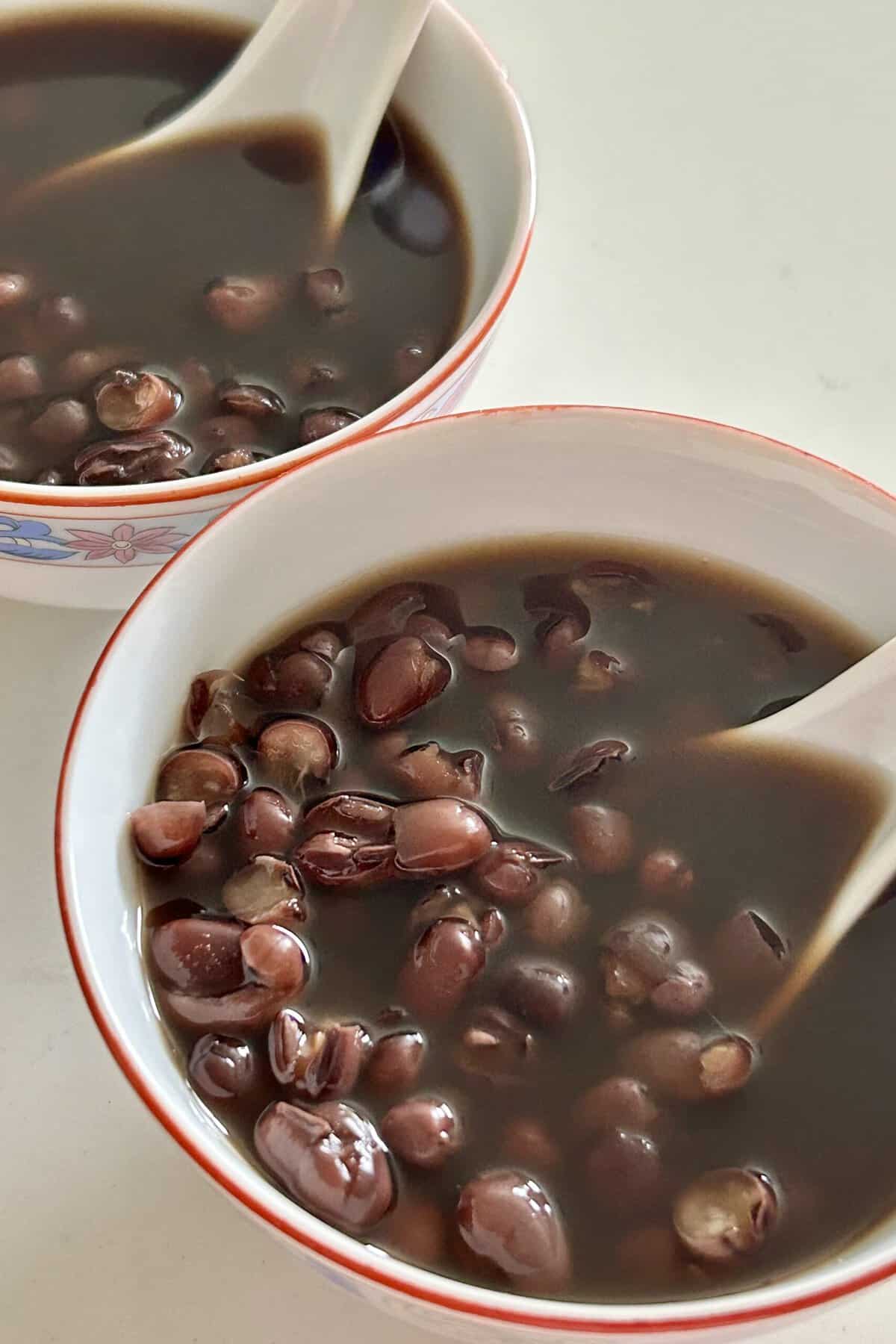 Cooked sweet red bean soup in a Chinese porcelain bowl and a spoon