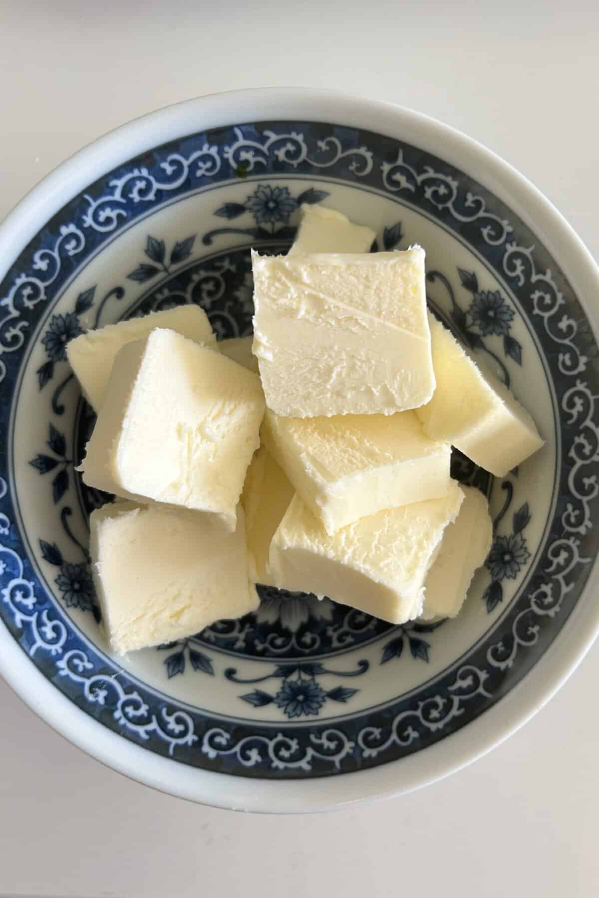 Cut up butter in a blue porcelain bowl ready to put in microwave to melt the butter