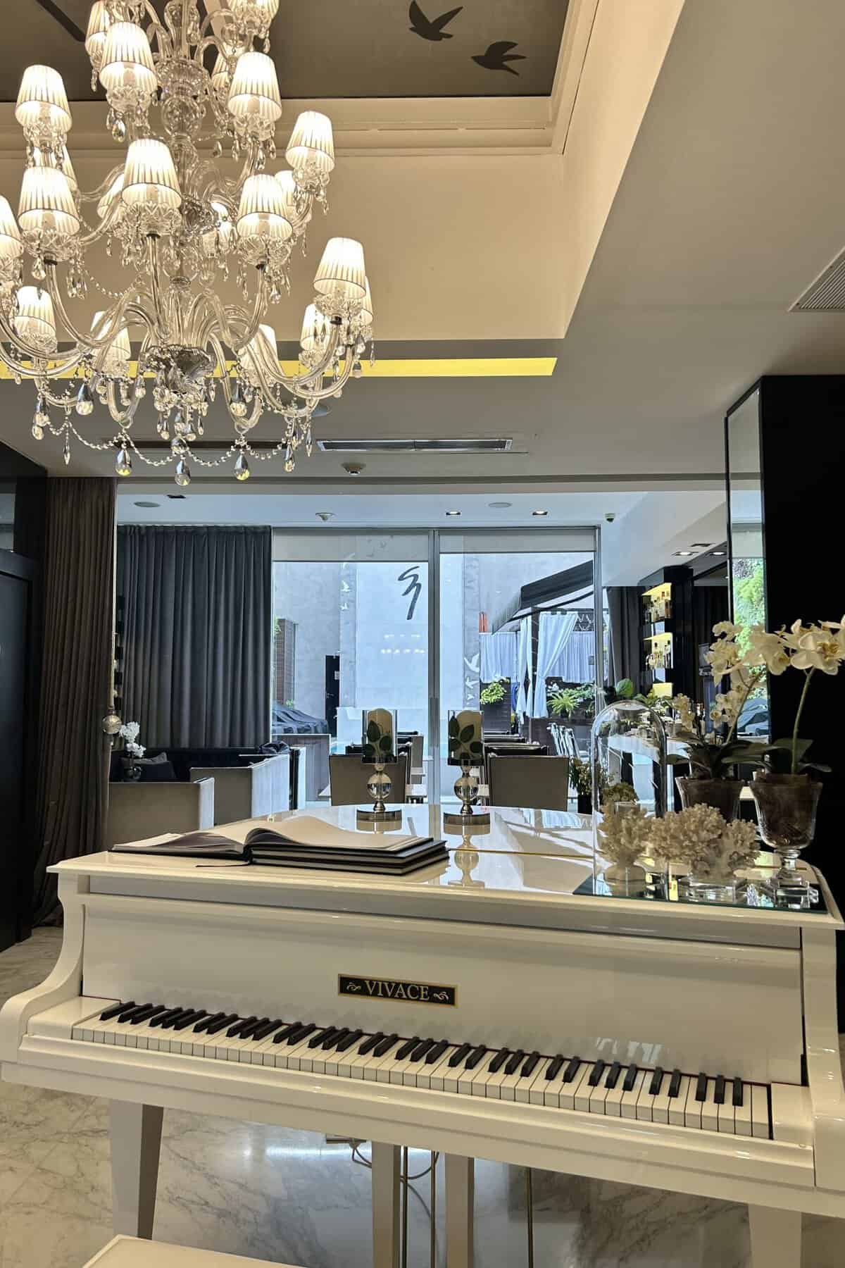 Lobby of 1828 Smart Hotel in Buenos Aires. It has a white grand piano, art deco sofas and dining area.