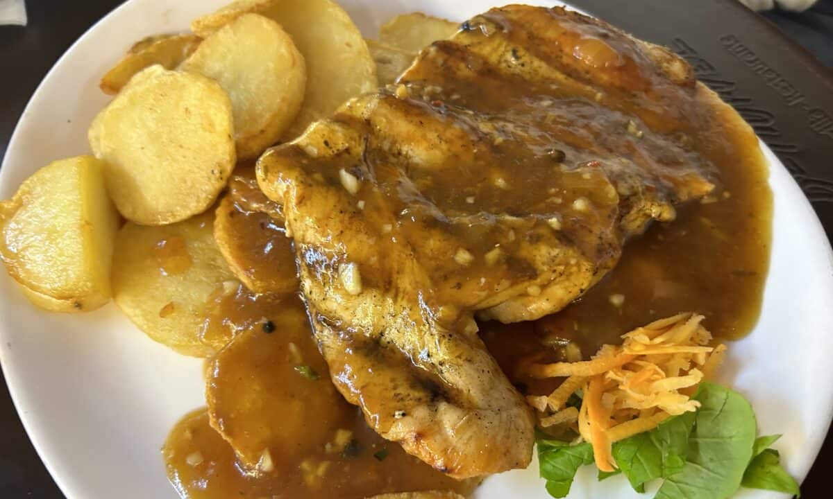 Two pieces of tender juicy chicken with steak sauce and fried sliced potatoes at El Desnivel