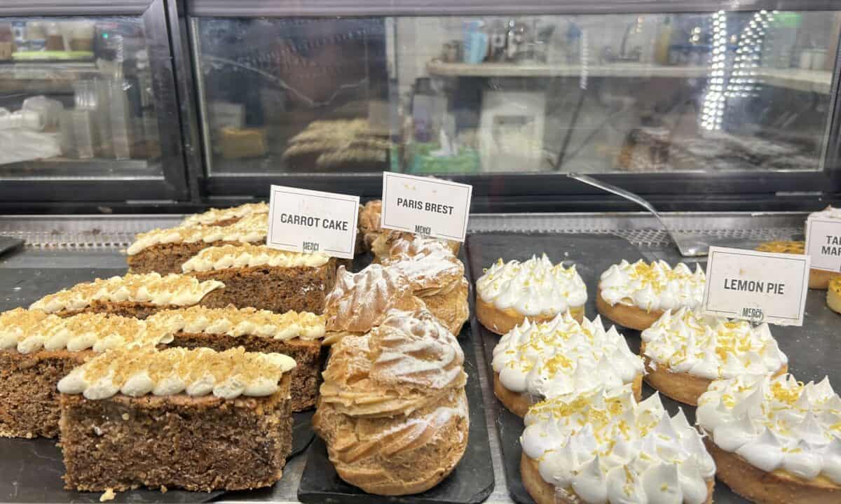 Carrot cake, Paris brest, and lemon pie display at a bakery in San Telmo Market