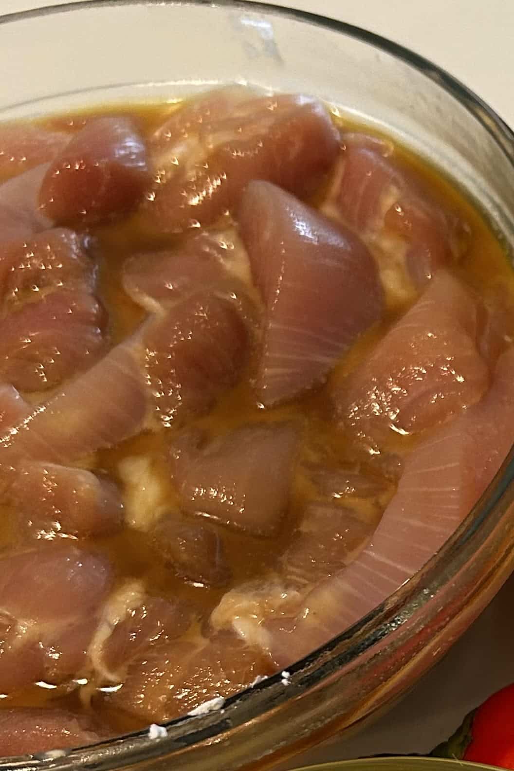 Chicken thigh meat marinated with soy sauce, egg yolk and cornstarch in a bowl.