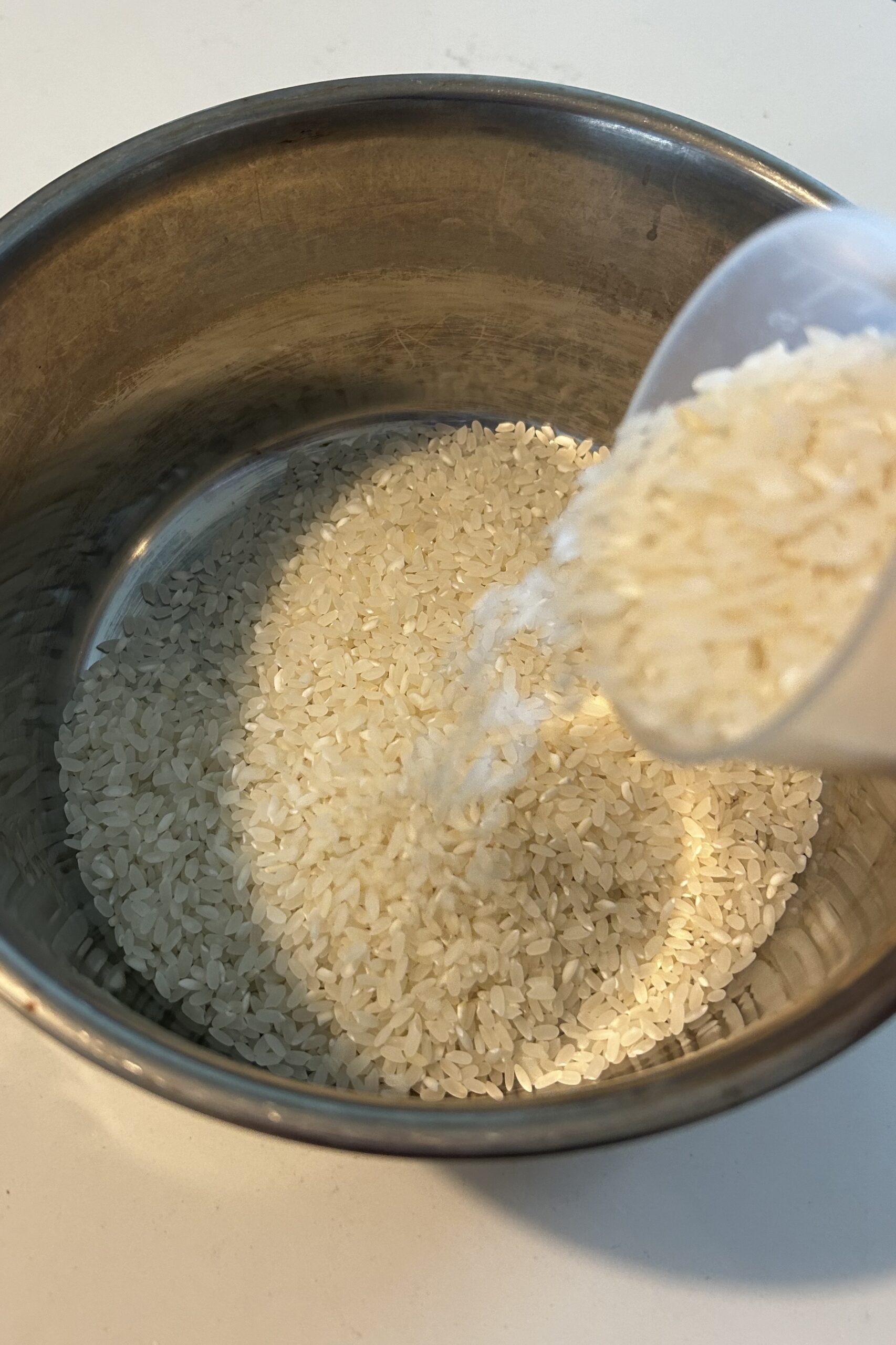 Pouring uncooked rice from measuring cup to the inner pot of Tatung rice cooker