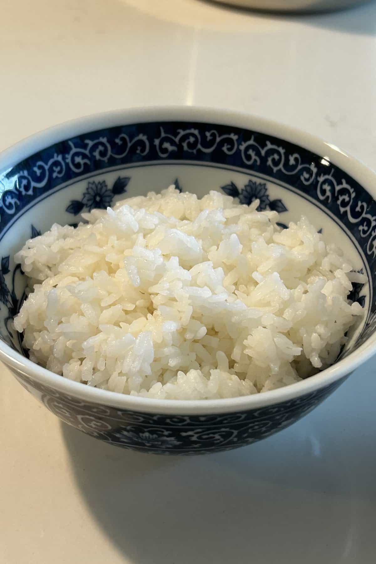 Cooked white rice in a Chinese blue and white ceramic bowl.