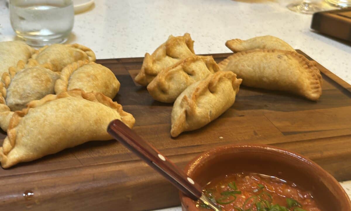 Cooked empanada on a wooden board with Yasgua dipping sauce