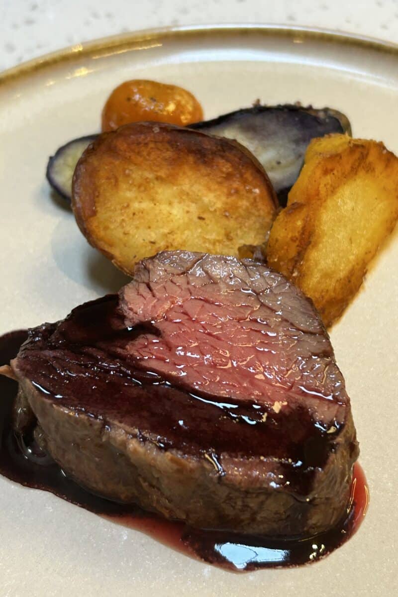 Medium rare tenderloin and potato carrot purple yam on a plate