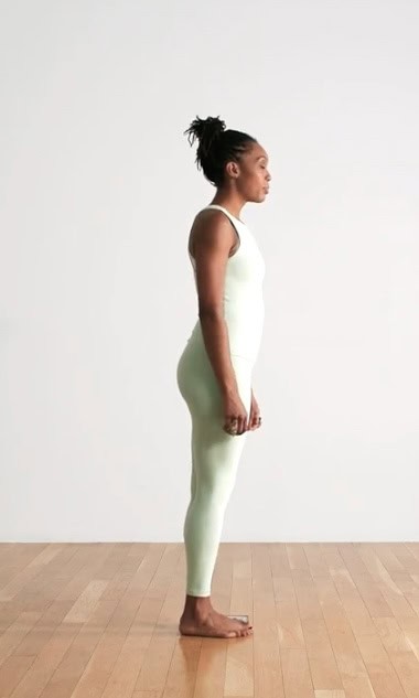 A yogi wearing light green yoga jumpsuit in Mountain Pose