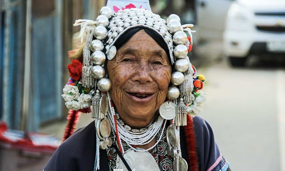 An old lady wearing a head piece with lots of decorations. She was smiling.