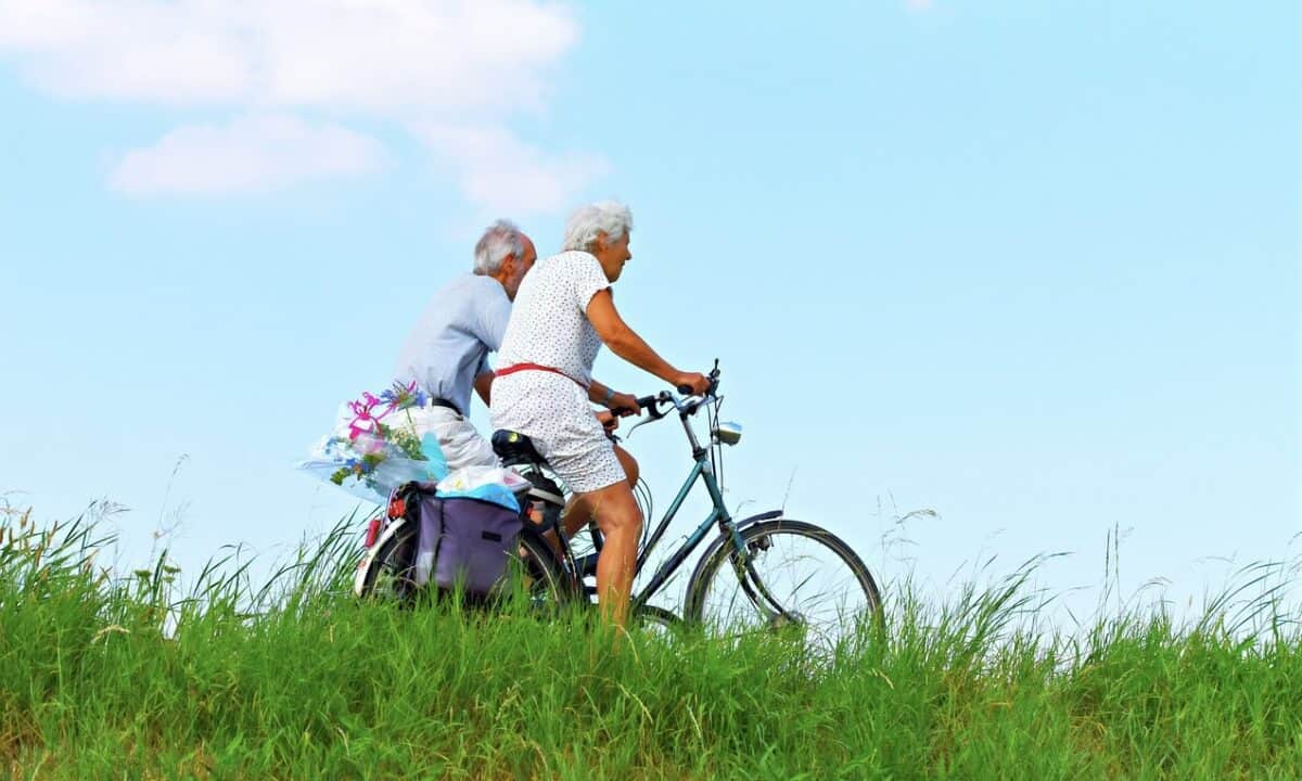 An old couple riding bicycles in a breezy day with blue skies