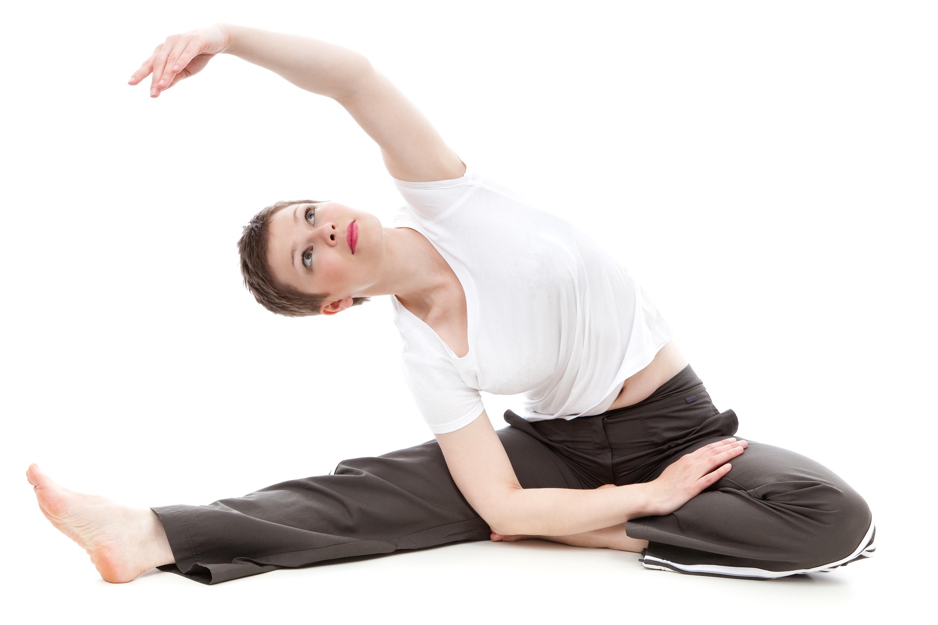 A woman wearing white top and black pants doing yoga (side bend)