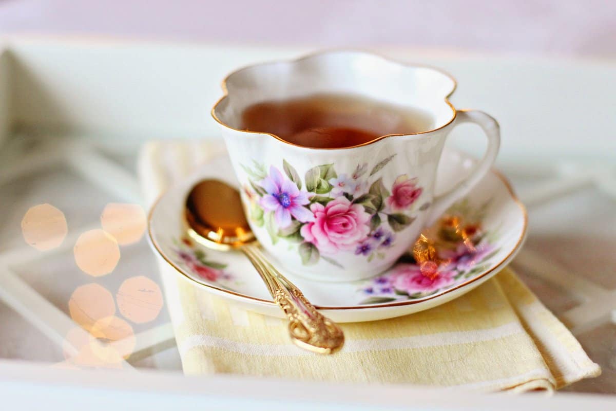 Tea in a floral tea cup with gold rim on a saucer with a gold teaspoon