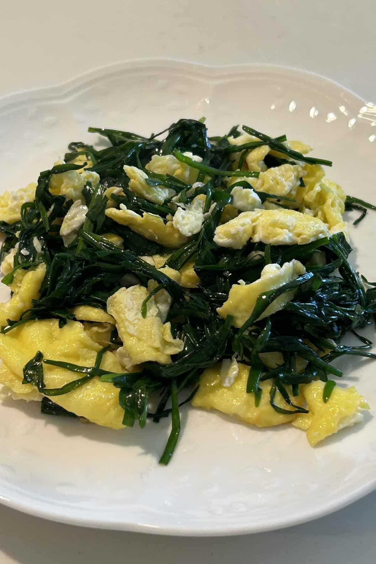 Scrambled eggs and Chinese chives on a white plate